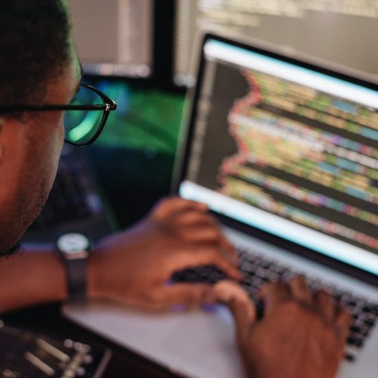 Black male in front of computer screen coding mobile app, web development, computer programming